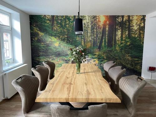 a dining room with a wooden table and a forest mural at Ferienhaus Harzcolor Wernigerode in Wernigerode