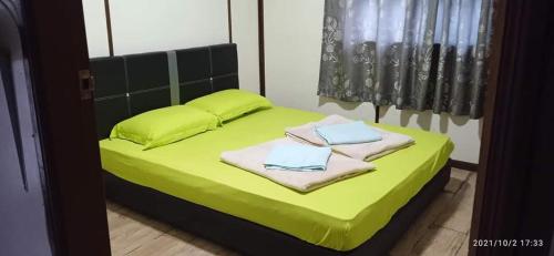 Un dormitorio con una cama verde con toallas. en Dongorit Cabin House 1 en Kundasang