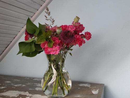 a glass vase filled with pink flowers on a table at DOM GOŚCINNY PTASZARNIA - NATURA-Free PARKING in Świnoujście