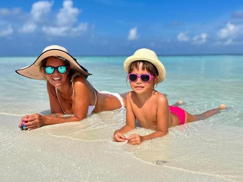 a woman and a child laying on the beach at By the shade Maldives in Hangnaameedhoo