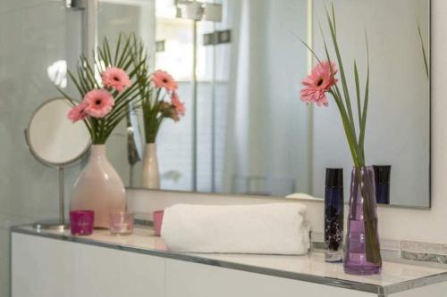 a bathroom counter with vases and flowers on a mirror at Ferienwohnung Auszeit in Scharbeutz