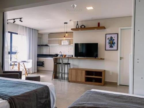 a room with two beds and a kitchen with a television at Diamond Hotéis e Flats in São Lourenço