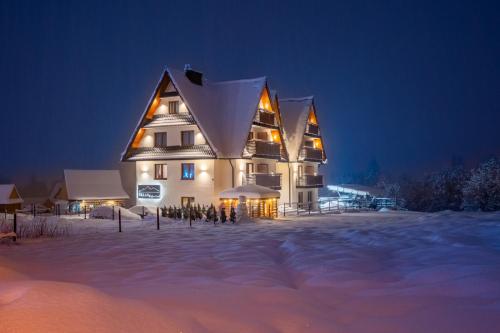 a large building in the snow at night at Villa 84 & Apartments Jacuzzi & Sauna in Zakopane