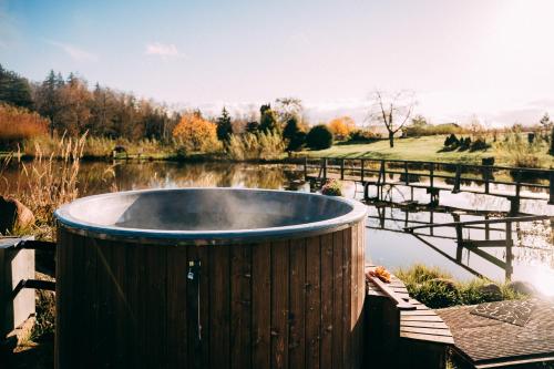 a wooden tub sitting next to a body of water at Ragnar Glamp Milzkalne Forest in Rauda