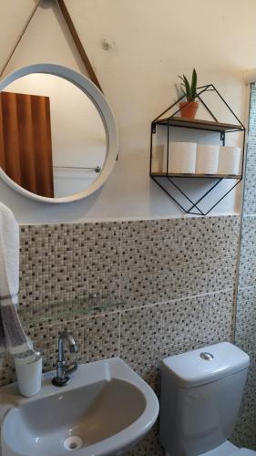 a bathroom with a sink and a mirror and a toilet at Casa Quaresmeira in Palmeiras