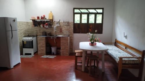 a kitchen with a table and a kitchen with a refrigerator at Casa Quaresmeira in Palmeiras