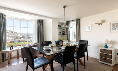a dining room with a glass table and black chairs at Coral in Brixham