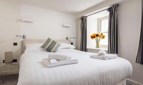 a white bed with towels on it with a window at Coral in Brixham