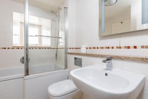 a white bathroom with a sink and a shower at Coral in Brixham