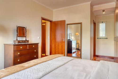 a bedroom with a bed and a dresser and a television at Lidia's Place, a Home in Madeira in Ponta do Sol