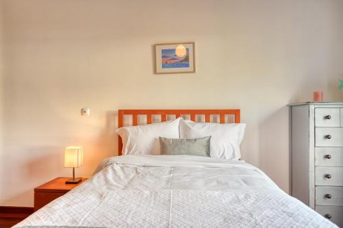 a bedroom with a white bed with a lamp and a dresser at Lidia's Place, a Home in Madeira in Ponta do Sol