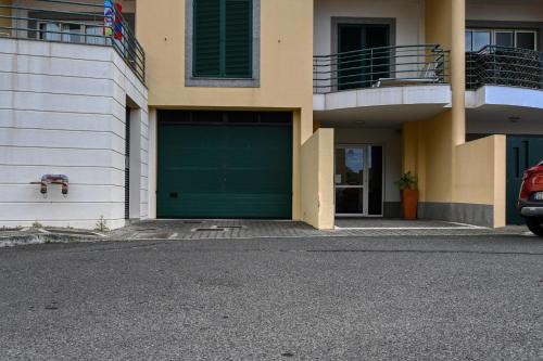 a green garage door on the side of a building at Lidia's Place, a Home in Madeira in Ponta do Sol