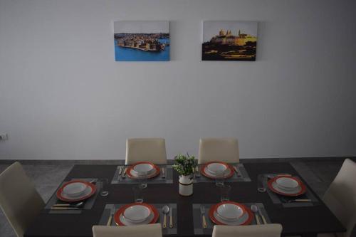 a dining room table with red and white plates and chairs at Lovely 3-bedroom apartment in L-Iklin in LʼInglin