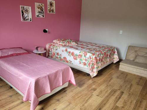 a bedroom with two beds and a chair at POUSADA Chacara ENTRE NÓS in Holambra