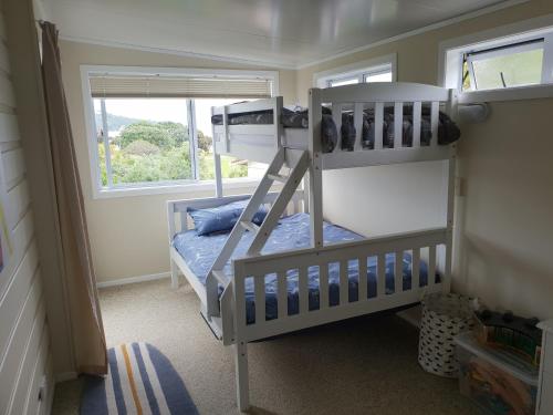 a bedroom with two bunk beds and a window at Stanmore Bay Beachfront Cottage in Whangaparaoa
