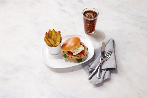 a sandwich and french fries on a plate with a drink at EVEN Hotel New York - Times Square South by IHG in New York