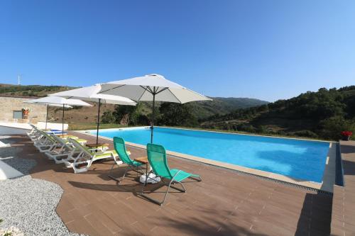a swimming pool with chairs and umbrellas next to it at Quinta da Alqueidosa - Casa de Campo 