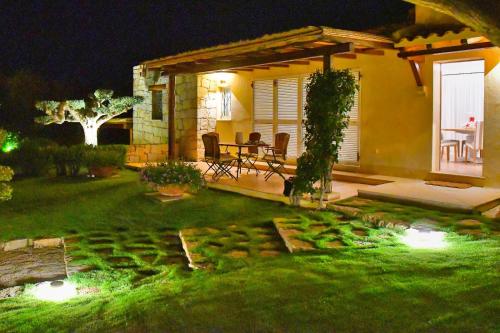 a garden at night with a table and chairs at [Villa indipendente piscina privata] e vista mare in Cala Bitta