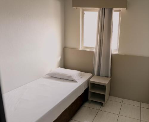 a small bedroom with a bed and a window at OK Inn Hotel Criciúma in Criciúma
