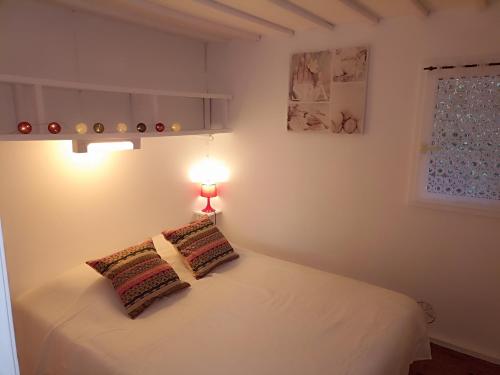 ein Schlafzimmer mit einem weißen Bett mit einer Lampe in der Unterkunft Les cabanes de l'île aux oiseaux Guern in Guern