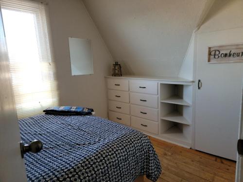 a bedroom with a bed and a dresser and a window at Maison du bord du fleuve à 5 min du centre ville in Rimouski