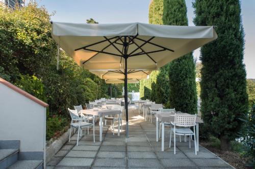 a patio with white tables and chairs and an umbrella at Locanda agli Amici in Cortona