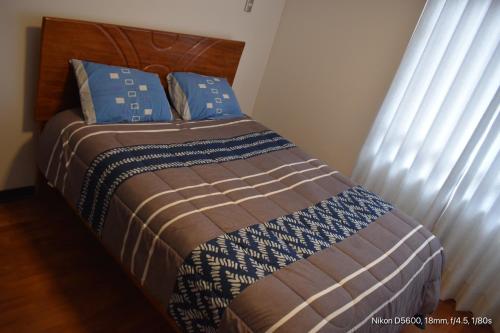 Cet appartement comprend une chambre dotée d'un lit avec des draps bleus et bruns et d'une fenêtre. dans l'établissement gabriel home, à Cusco
