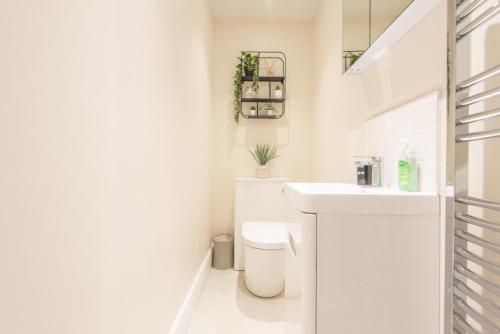 a white bathroom with a toilet and a sink at Bright, fresh, renovated 3 bedroom apartment in the heart of Montrose in Angus