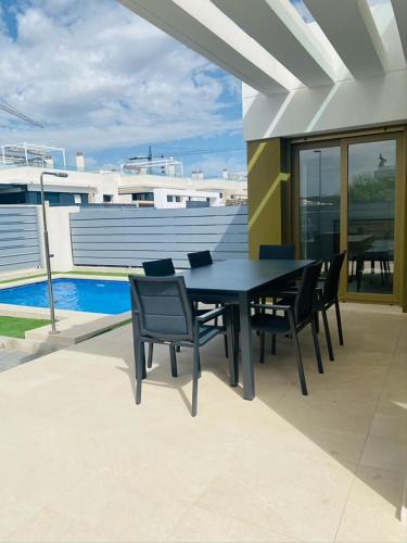 y balcón con mesa de comedor negra y sillas. en vistabella golf maui en Alicante