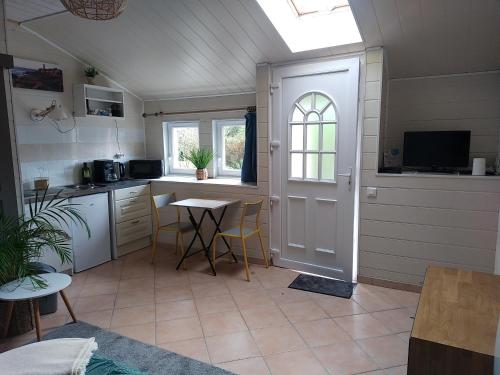 eine Küche mit einem Tisch, einem Fenster und einer Tür in der Unterkunft Studio 2 personnes Bannalec in Bannalec