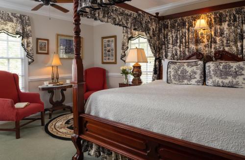 a bedroom with a canopy bed and red chairs at A Williamsburg White House Inn in Williamsburg