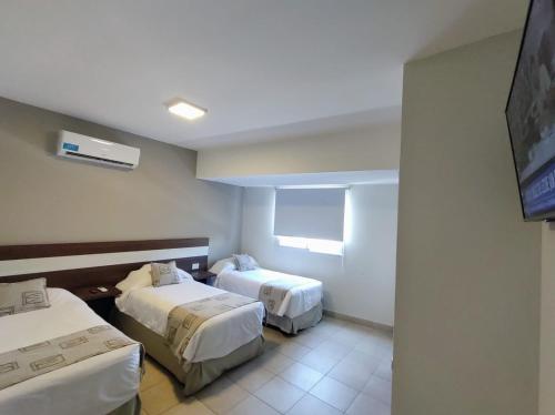 Urquiza Suites Salta في سالتا: غرفة فندقية بسريرين وتلفزيون بشاشة مسطحة