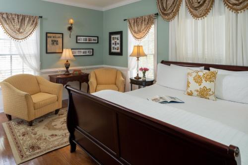 a bedroom with a large bed and two chairs at A Williamsburg White House Inn in Williamsburg