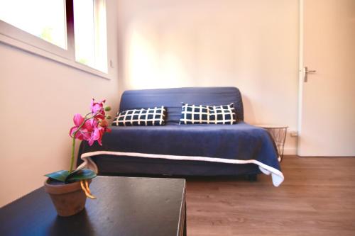 a blue bed in a room with a plant on a table at Les Hibiscus in Saint-Mandrier-sur-Mer