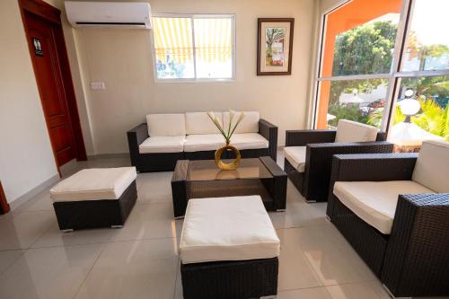 a living room with couches and a table and windows at Vivy Hill's Hotel in Port-au-Prince
