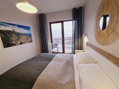 a bedroom with a large bed and a mirror at Apartament E5 Karpatia - 5D Apartamenty in Karpacz