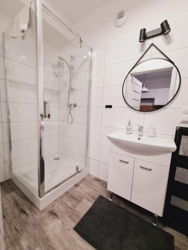 a bathroom with a shower and a sink and a mirror at Apartament E5 Karpatia - 5D Apartamenty in Karpacz