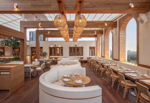 a restaurant with white tables and chairs and windows at Mondrian Los Angeles in Los Angeles