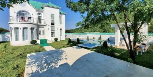ein großes weißes Haus mit einem Pool im Hof in der Unterkunft Qafqaz Manor Grafana in Qəbələ