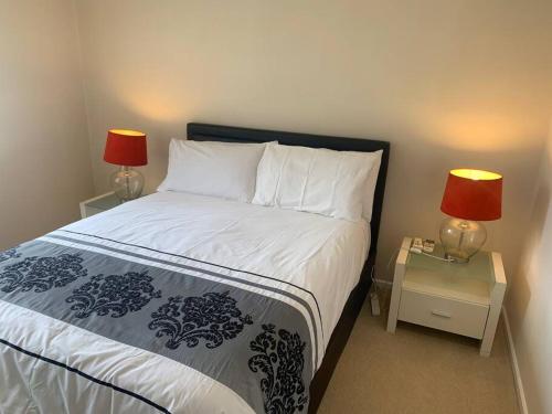 a bedroom with a bed with two lamps on tables at Cheerful 3 bedrooms with free parking in Kingswood