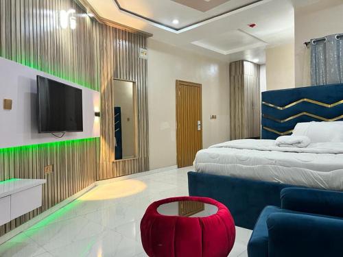 a bedroom with a bed and a tv and a red stool at Clique Court Hotel & Suite in Opete
