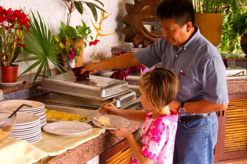 Ein Mann und ein kleines Mädchen bereiten Essen in einer Küche vor. in der Unterkunft Casa del Mar Cozumel Hotel & Dive Resort with free access to an exclusive beach club in Cozumel