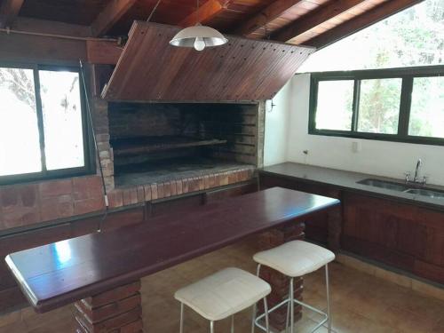 cocina con mesa y 2 taburetes frente a una chimenea en Casa en el delta con acceso terrestre en Belén de Escobar