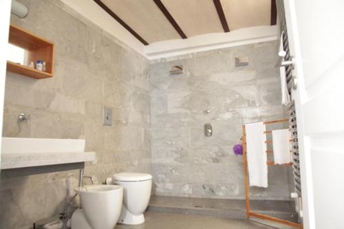 a bathroom with a white toilet and a sink at Le Malve Cave Retreat in Matera