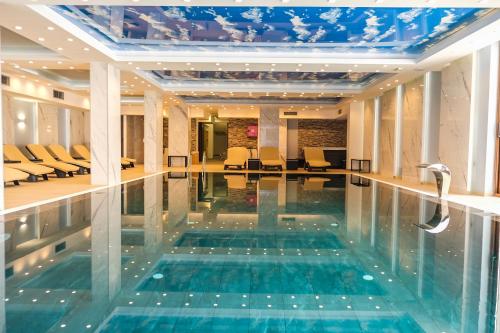 a swimming pool in a hotel lobby with chairs at President Kop Alex in Kopaonik