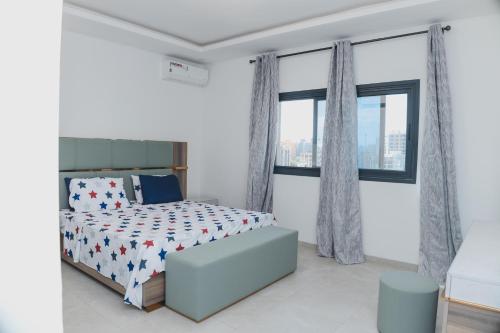 ein weißes Schlafzimmer mit einem Bett und Fenstern in der Unterkunft Appartment Luxe CAPUCINE dans la Zone B Dakar in Fass