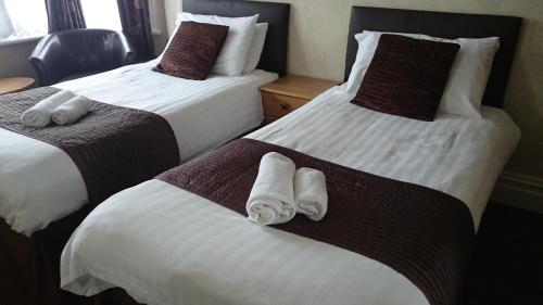 two beds in a hotel room with towels on them at Woodthorpe Hotel in Skegness