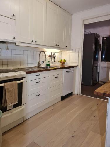 a kitchen with white cabinets and a sink and a refrigerator at Archipelago villa, cabin & sauna jacuzzi with sea view, 30 minutes from Stockholm in Tyresö