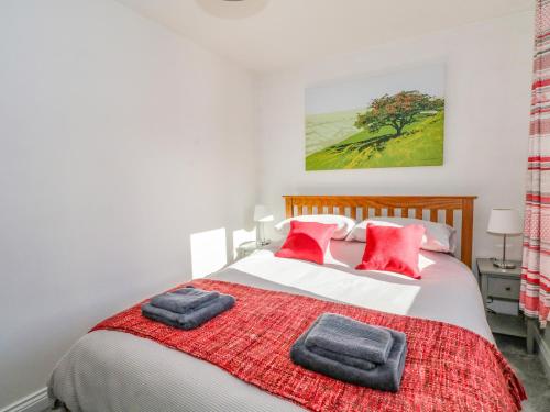 Un dormitorio con una cama con almohadas rojas. en 6 Hunters Green Close, en Chinley