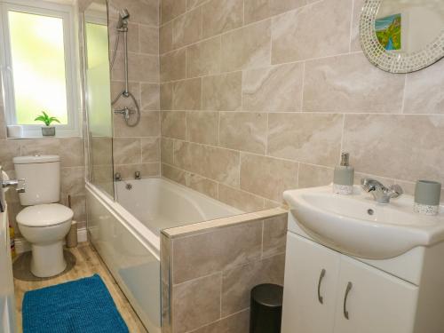 a bathroom with a sink and a toilet and a tub at 6 Hunters Green Close in Chinley
